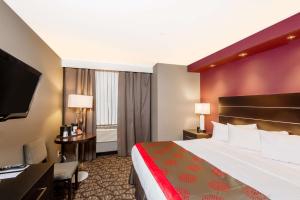 a hotel room with a bed and a desk and a television at Ramada by Wyndham Niagara Falls by the River in Niagara Falls