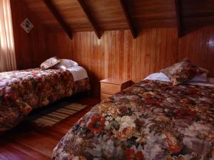 a bedroom with two beds and wooden walls at La Cabaña de Noa in Oxapampa