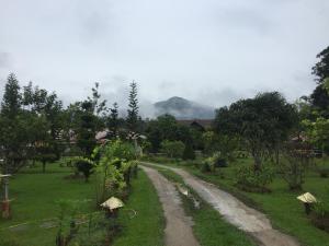 a dirt road through a village with a mountain at Happy Paradise in Kampung Janda Baik