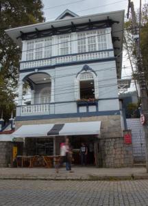 a man walking in front of a blue building at Hotel Cidade Imperial in Petrópolis