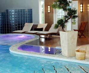a pool with chairs and a palm tree in a hotel room at Arendal Herregaard Spa & Resort in Arendal