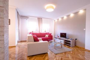a living room with a red couch and a tv at Apartman Arte in Novi Sad