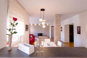 uma sala de estar com uma mesa com um vaso com uma rosa em Apartman Arte em Novi Sad