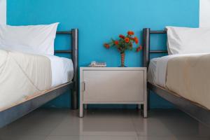 two twin beds with a vase of flowers on a night stand at Noble House Chiangmai in Chiang Mai
