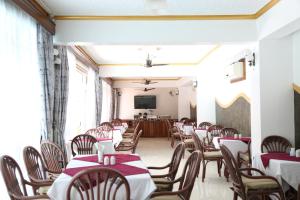 a dining room with tables and chairs and a television at Prestige Leisure Hotel in Mtwapa