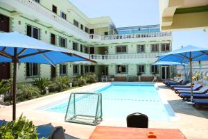 a pool in the courtyard of a hotel with blue umbrellas at Prestige Leisure Hotel in Mtwapa