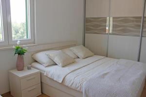ein weißes Bett mit zwei Kissen im Schlafzimmer in der Unterkunft Happy garden house in Kožino