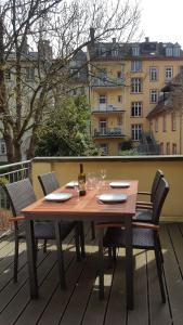 einen Holztisch mit Stühlen und eine Flasche Wein auf dem Balkon in der Unterkunft Ferienwohnungen Neckarblick - Heidelberg Altstadt in Heidelberg