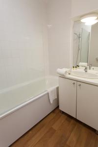 La salle de bains blanche est pourvue d'une baignoire et d'un lavabo. dans l'établissement Séjours & Affaires Reims Clairmarais, à Reims