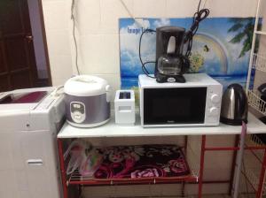 d'un four micro-ondes et d'une cafetière sur une étagère. dans l'établissement Addeen homestay, à Kampong Kemaman