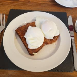 un piatto bianco con un pezzo di pane tostato con panna montata di The Tables Guest House a Dunvegan Altre 31 foto