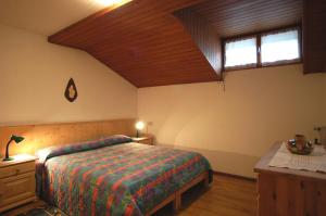 a bedroom with a bed and a wooden ceiling at Casa De Biasio PM in Falcade +2 photos