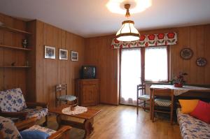 een woonkamer met houten lambrisering, een tv en een tafel bij Casa De Biasio PM in Falcade