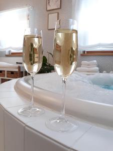 two glasses of white wine sitting on a bath tub at Ferienhaus Rosenhof in Weidenbach