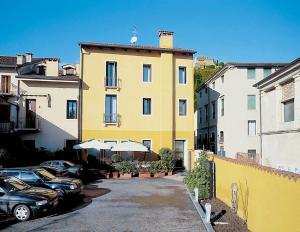 um edifício amarelo com carros estacionados num parque de estacionamento em Hotel Due Mori em Marostica