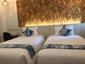 two twin beds in a room with a wall at UD Capital Hotel in Udon Thani