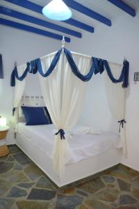 a bedroom with a white bed with blue curtains at Traditional Villa Relax in Zefiría