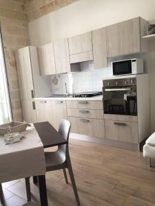 cocina con armarios blancos, mesa y comedor en Stella di Mare Dimora Charme, en Polignano a Mare
