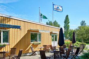 un patio con mesas, sillas y una bandera en Frederiksværk Camping & Hostel en Frederiksværk