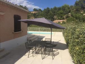 un patio con mesa, sillas y sombrilla en Maison Minervois, en Agel