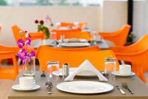a dining room with tables and orange chairs at Sanctum Suites Whitefield Bangalore in Bangalore
