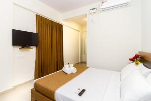 a hotel room with a bed and a flat screen tv at Sanctum Suites Whitefield Bangalore in Bangalore
