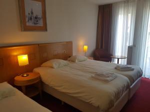 a hotel room with two beds and two lamps at Hotel 2000 Valkenburg in Valkenburg