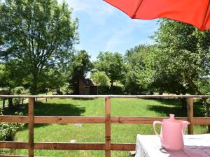 a pink tea pot sitting on a table with an umbrella at Bright holiday home in Gascony with garden in Gâcogne