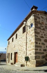 un edificio in pietra sul lato di una strada di Casa Rural El Molino I a San Bartolomé de Pinares