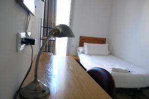 a room with a bed and a desk with a lamp at Pigal in Tarragona