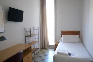 a bedroom with a bed and a desk and a television at Pigal in Tarragona