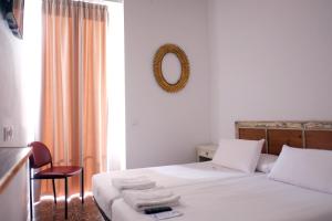 a bedroom with a white bed with a mirror and a chair at Pigal in Tarragona