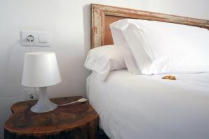 a bed with white pillows and a table with a lamp at Pigal in Tarragona
