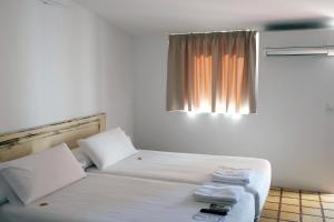 a bedroom with a bed with white sheets and a window at Pigal in Tarragona