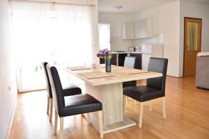 a dining room table with black chairs and a kitchen at Family house Branka in Peroj
