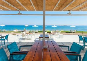 a wooden table and chairs with the beach in the background at Aptera Beach Apartment in Kato Daratso