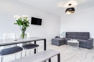 a living room with a couch and a table with flowers at Elite Apartments Oliwa Business Center in Gdańsk