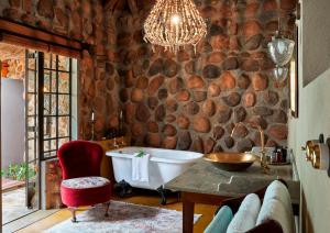 a bathroom with a stone wall with a tub and a chair at Geiger's Camp by NEWMARK in Timbavati Game Reserve