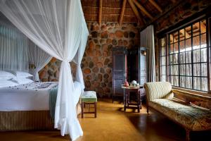 ein Schlafzimmer mit einem Bett, einem Sofa und Fenstern in der Unterkunft Geiger's Camp by NEWMARK in Timbavati Game Reserve