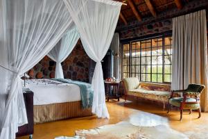 a bedroom with a bed and a chair and a window at Geiger's Camp in Timbavati Game Reserve by NEWMARK in Timbavati Game Reserve