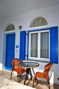 a table and chairs in a room with blue doors at Tinos Koralli in Tinos Town