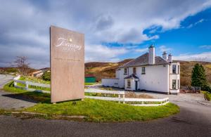 a sign in front of a white house and a building at Toravaig House Hotel in Teangue