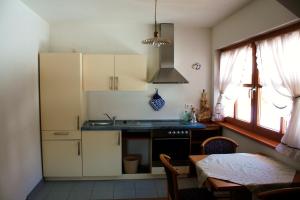cocina con armarios blancos, fregadero y mesa en Le Maier, en San Vigilio Di Marebbe