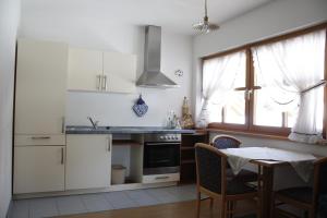 una cocina con electrodomésticos blancos y una mesa con sillas. en Le Maier, en San Vigilio Di Marebbe