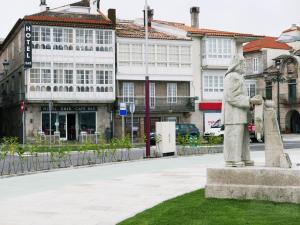 a statue of a man standing next to a building at Hotel Cais in Baiona