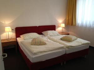 a bed with two pillows on it with two lamps at Restaurant Waldmeisterei in Gera