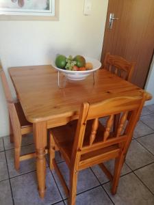 a bowl of fruit on a wooden table with chairs at A Wave from it all in Port Shepstone