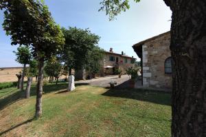 a building with a yard with trees in front of it at Agriturismo Bagnaia in San Quirico dʼOrcia