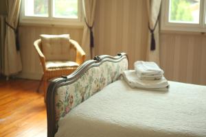 La chambre d'hotes du Parc في Podensac: غرفة نوم بسرير وكرسي ونوافذ
