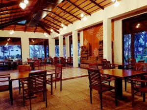 un restaurante con mesas y sillas de madera y ventanas en Vgp Golden Beach Resort, en Chennai